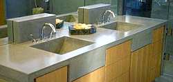 Juxtaposed against warm natural wood cabinets, a concrete countertop with integrated dual sinks produces a very modern look.