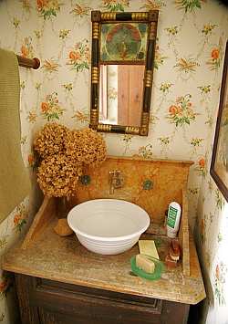 An old fashioned style bowl serves as the perfect sink basin in a country bathroom. Warm tones give this country bathroom a natural, earthy look.