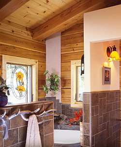 Wood, stone and a polished steel sculpture of a Deer antler as towel rack give this upscale bathroom a distinctive rustic charm.
