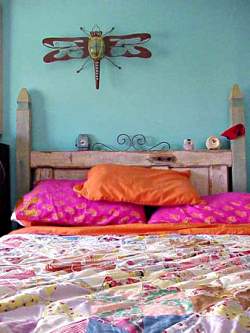The contrast of turquoise wall color against the bright accent orange and red pillows on the bed give this bedroom energy while retaining a more feminine look.