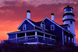 The iconic Cape Cod lighthouse keepers home shows the steep pitched roof, dormers and wraparound porch that have come to symbolize the cape cod style house.