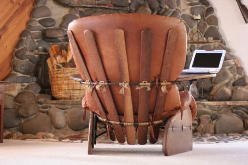 Country decor can blend with modern design elements. The distinctly modern shape of this chair has a rustic feeling with natural leather, wood planks and a stone hearth backdrop.