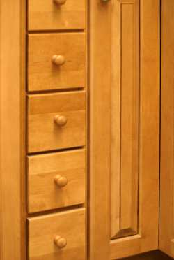 Kitchen drawer pulls may stand out or blend with the natural texture and shape of drawer fronts like these simple wood knobs.