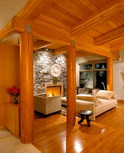 Warm and inviting, the living room matches the overall architecture and design cues of this home, with natural wood and a stone surround.