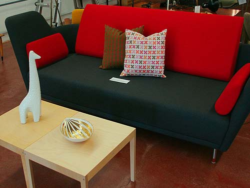 This retro sofa has been finished in black with contrasting bright red pillows. Simple geometric shapes like these square coffee tables are a hallmark of 1950s retro furniture.