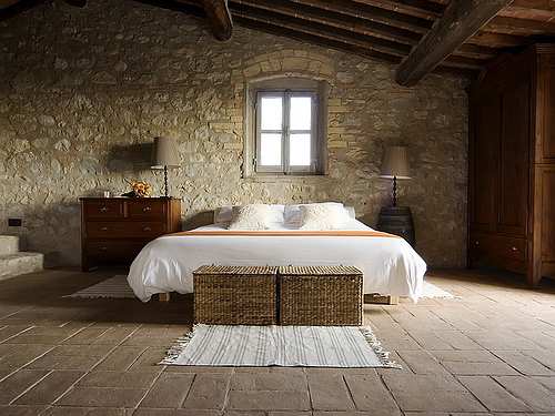 The texture of natural stone, open beam ceilings, furniture with clean, simple lines and the use of plain white bedding reveal this room can be in only one place; Tuscany, Italy.