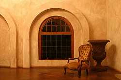 Full length arched windows, natural stone floors, textured walls and simple, uncluttered design define this upscale Tuscan style room.