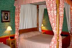 A Victorian four post bed with ornate canopy shows how fabric patterns are often repeated.